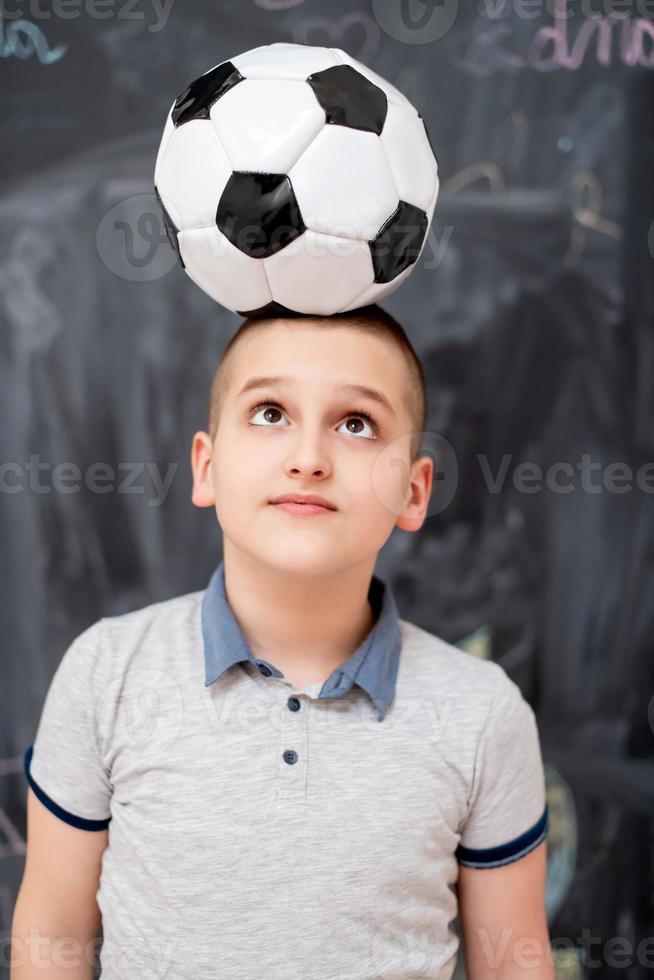 happy boy holding a soccer ball on his head photo