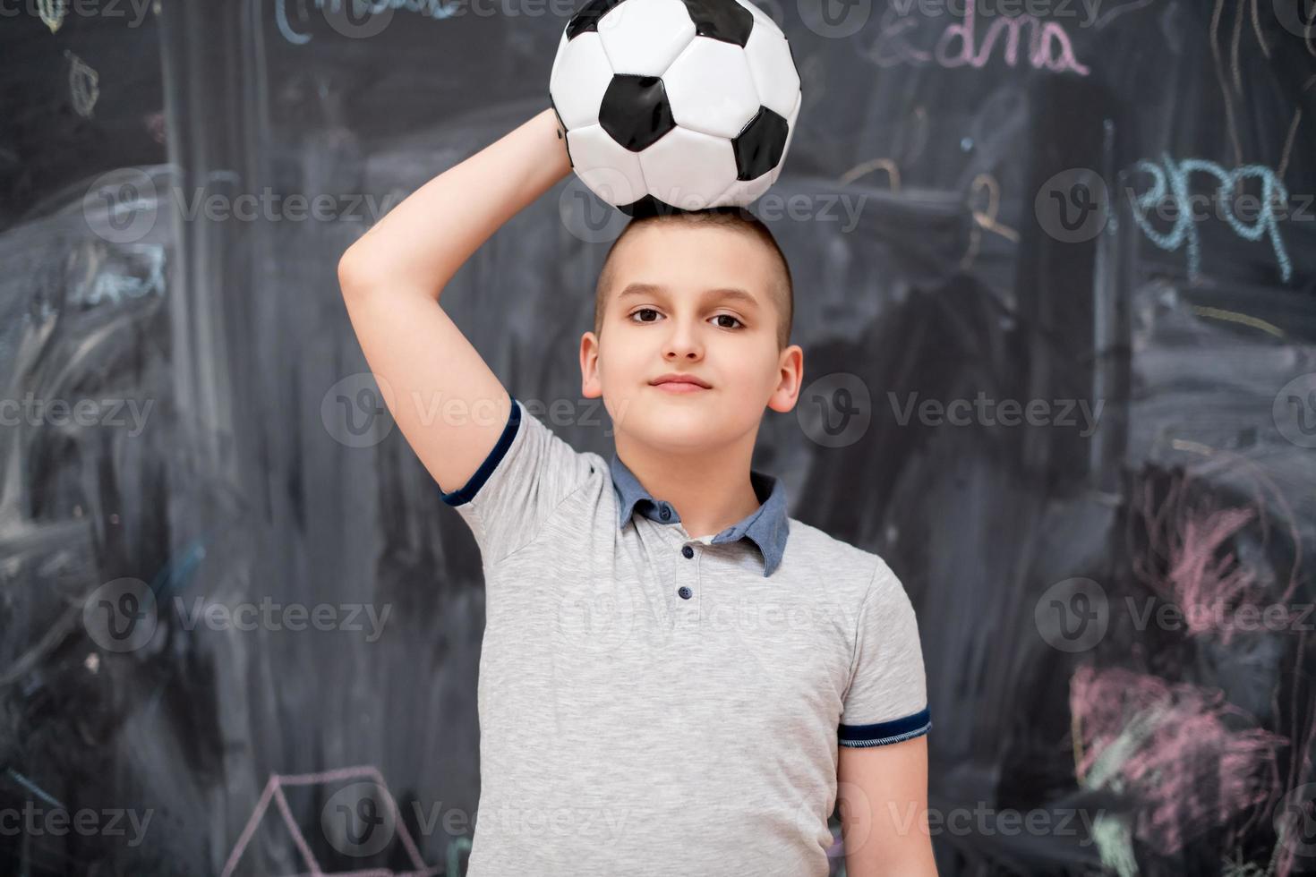 happy boy holding a soccer ball on his head photo