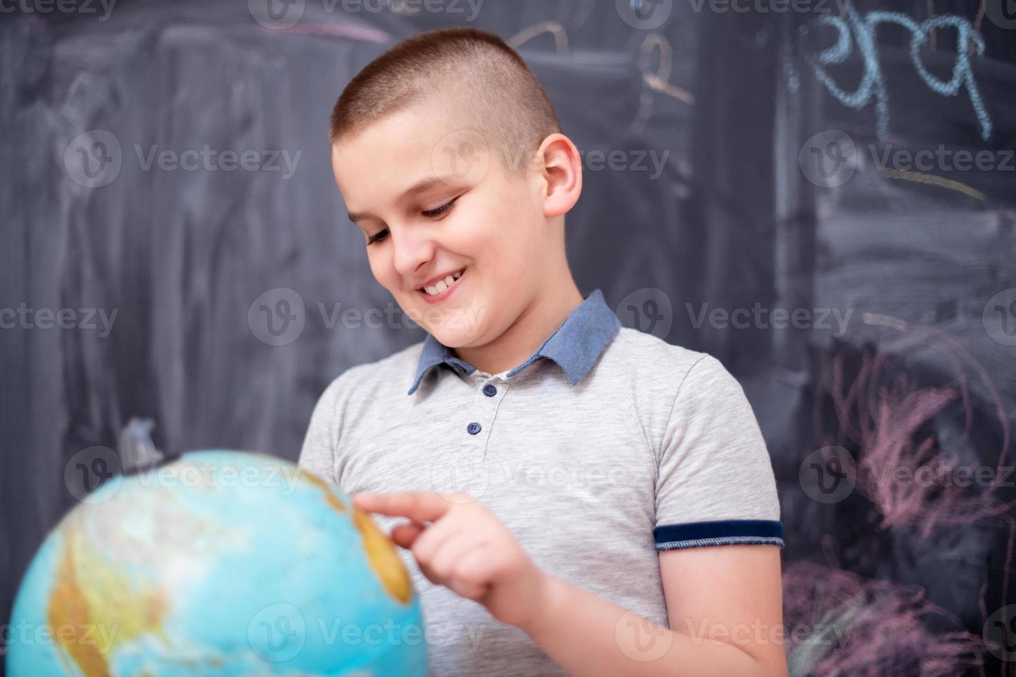 boy using globe of earth in front of chalkboard photo