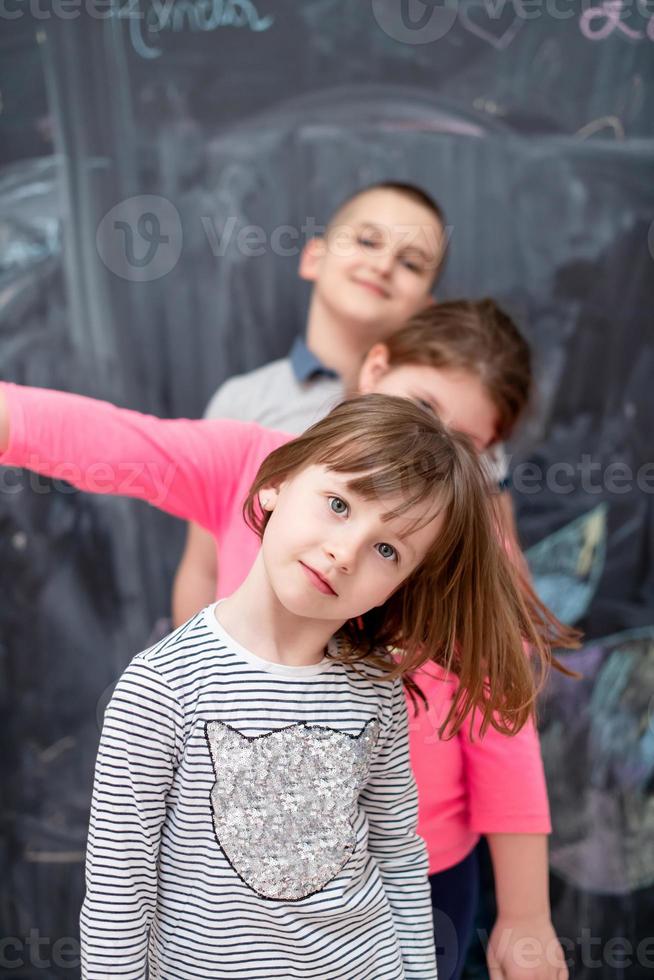 group of kids standing in front of chalkboard photo