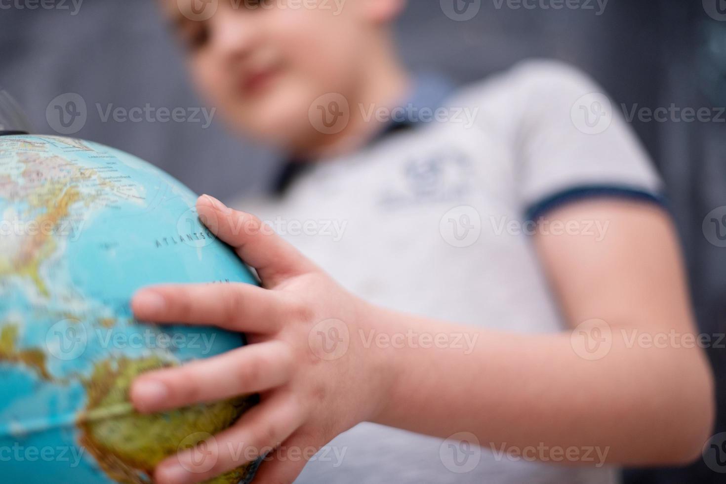 niño usando el globo terráqueo frente a la pizarra foto