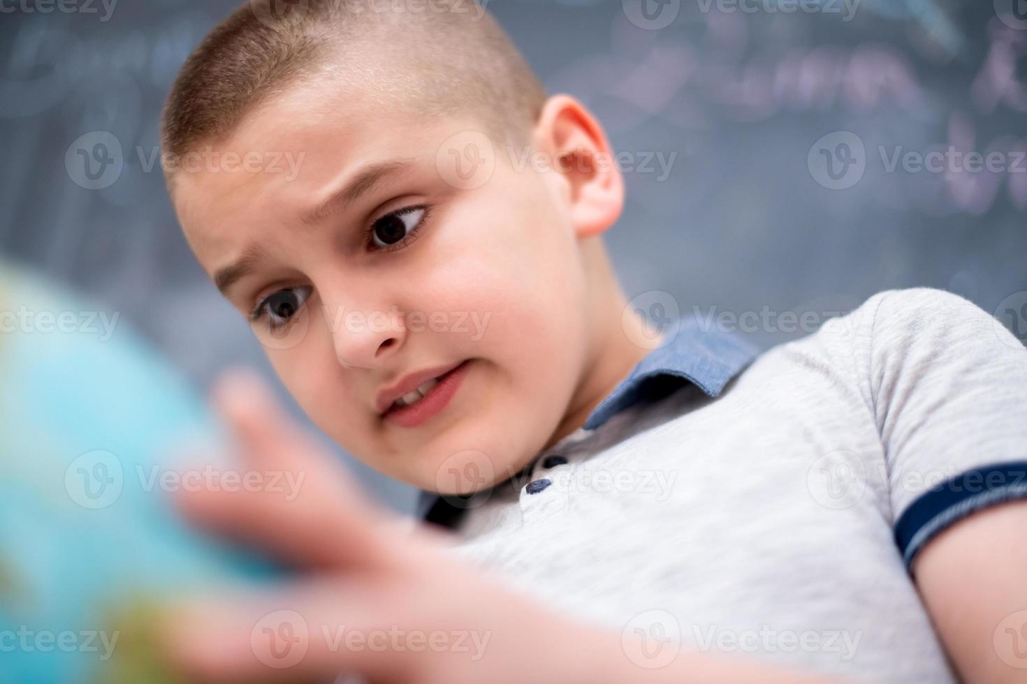 boy using globe of earth in front of chalkboard photo