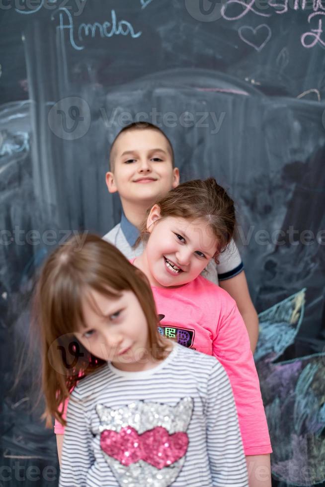 group of kids standing in front of chalkboard photo