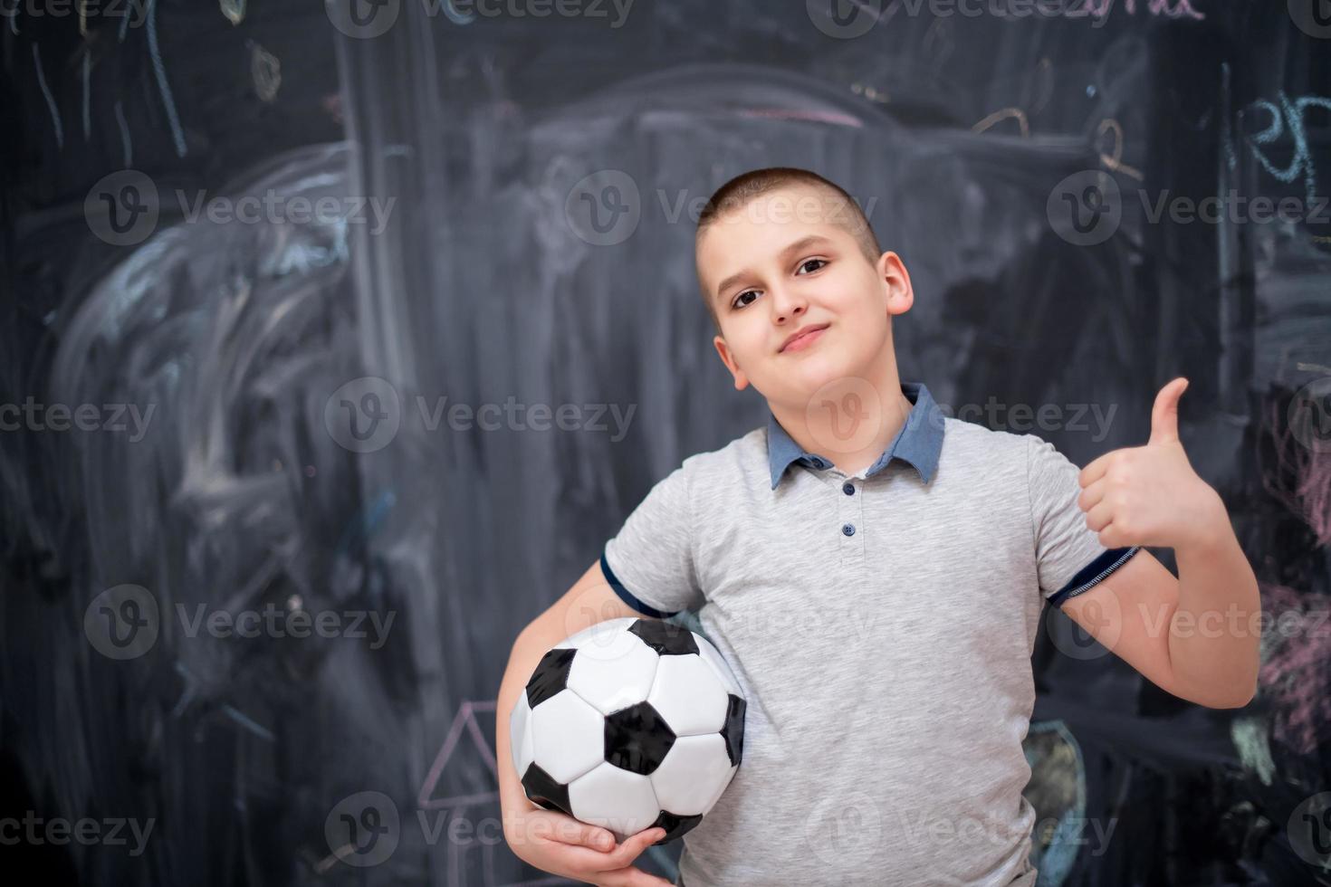 happy boy holding a soccer ball in front of chalkboard photo
