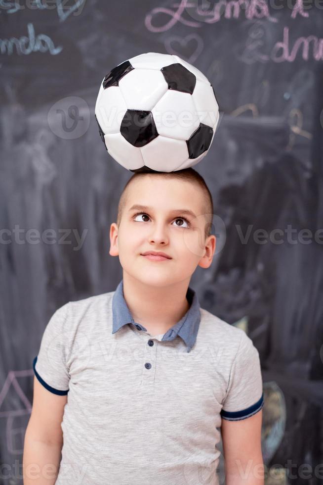 happy boy holding a soccer ball on his head photo