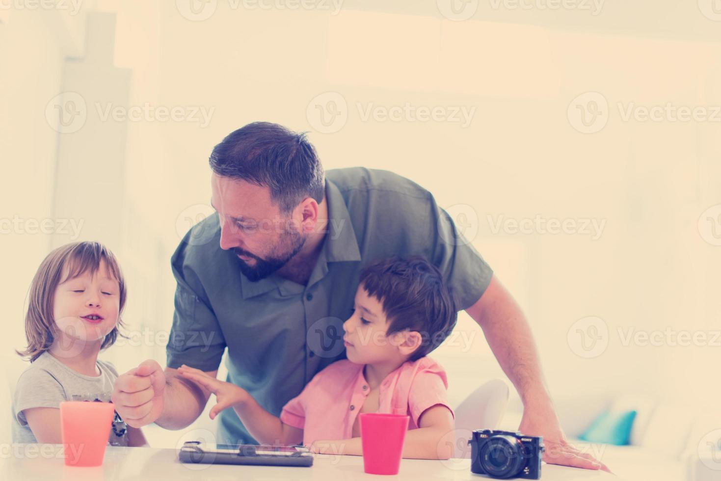 single father at home with two kids playing games on tablet photo