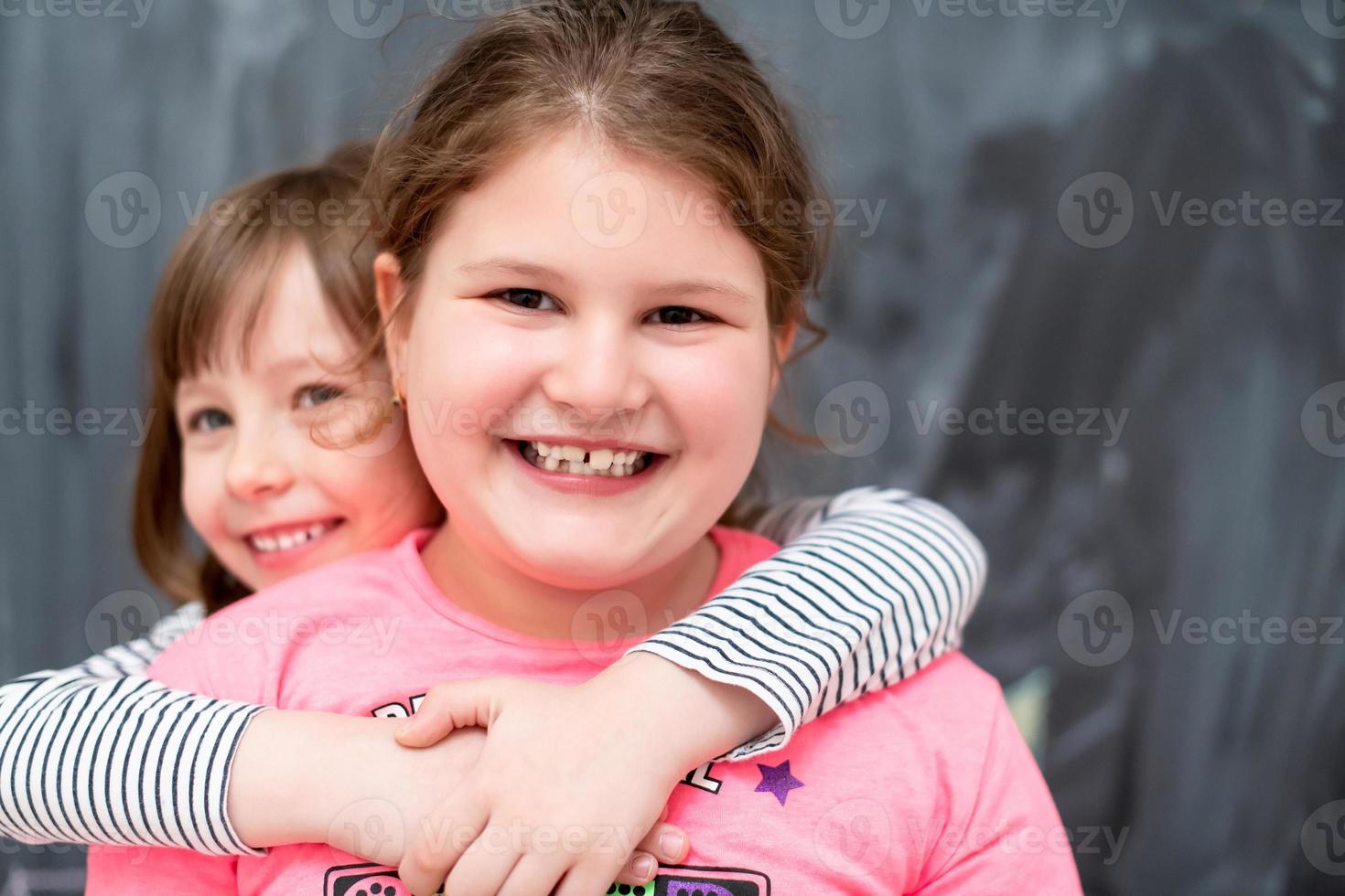 little girls hugging in front of chalkboard photo