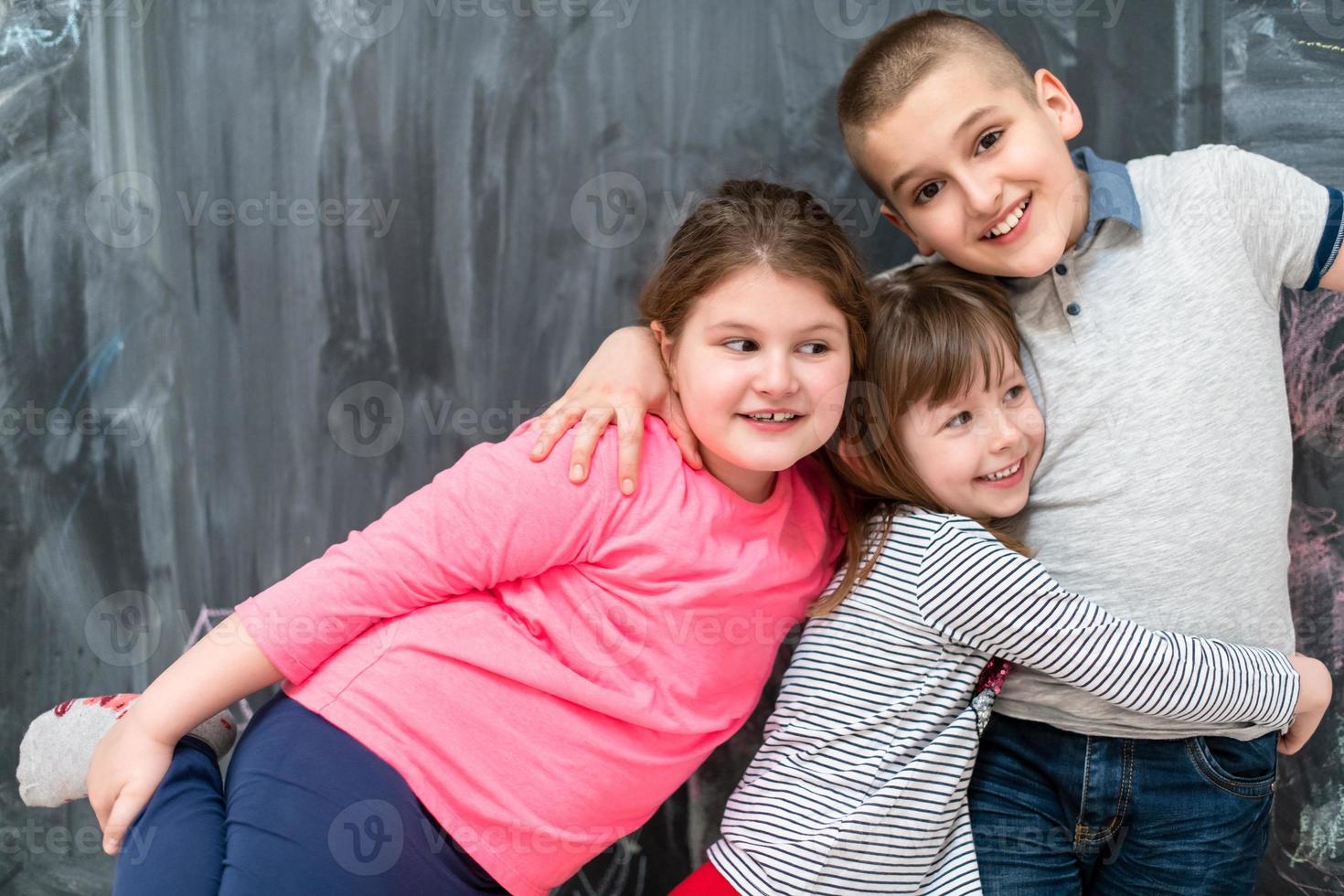 grupo de niños abrazándose frente a la pizarra foto