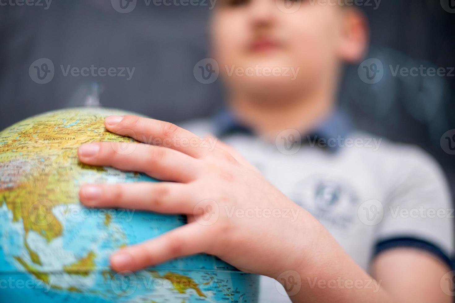 boy using globe of earth in front of chalkboard photo