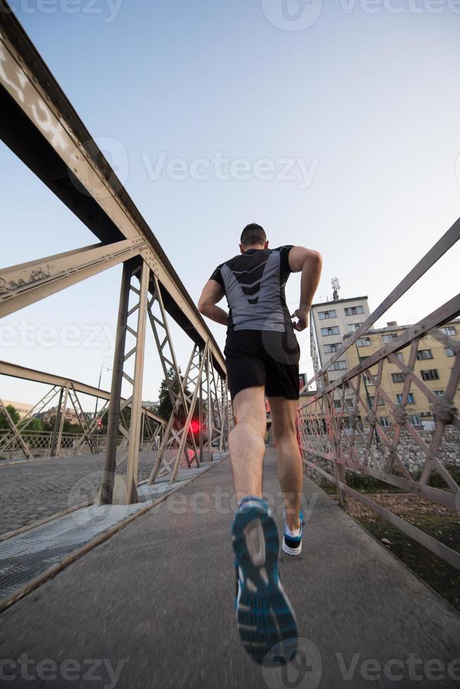 hombre corriendo por el puente en la mañana soleada foto