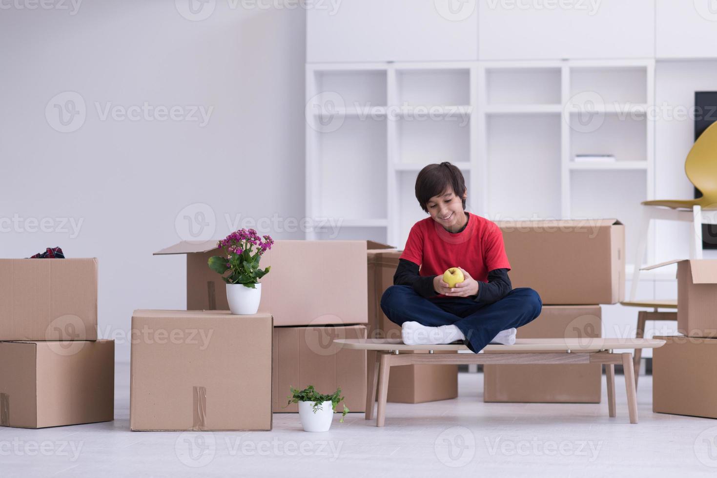 boy sitting on the table with cardboard boxes around him photo