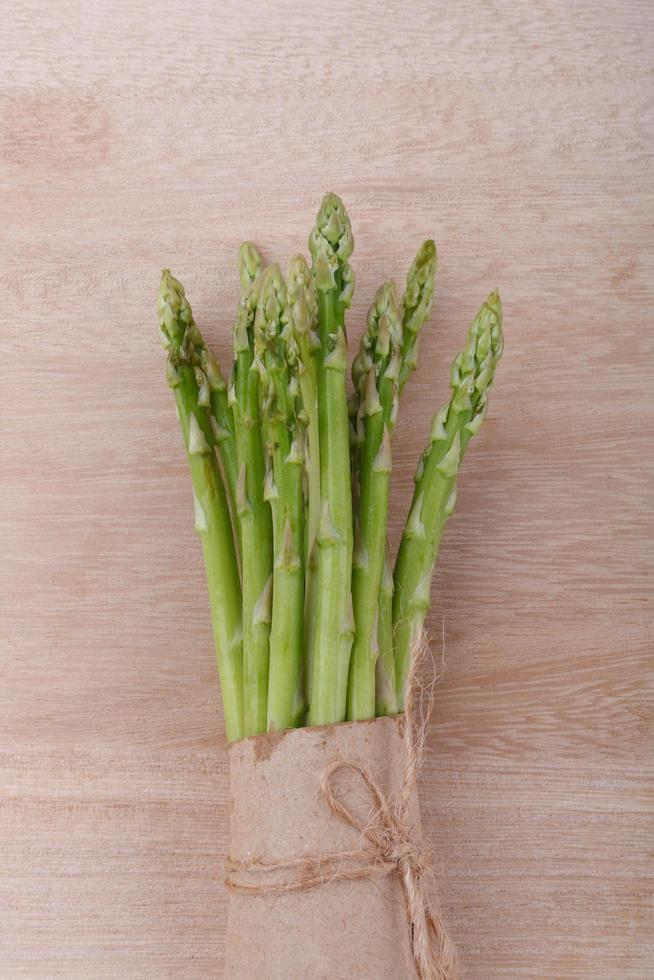 uncooked green asparagus tied with twine from above on wooden photo