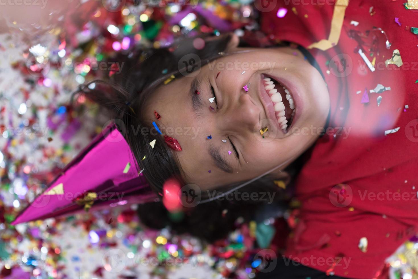 kid blowing confetti while lying on the floor photo