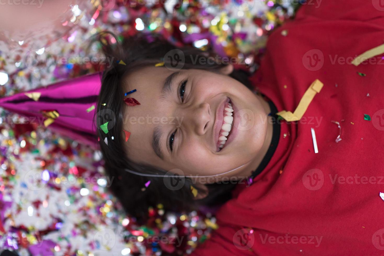 kid blowing confetti while lying on the floor photo