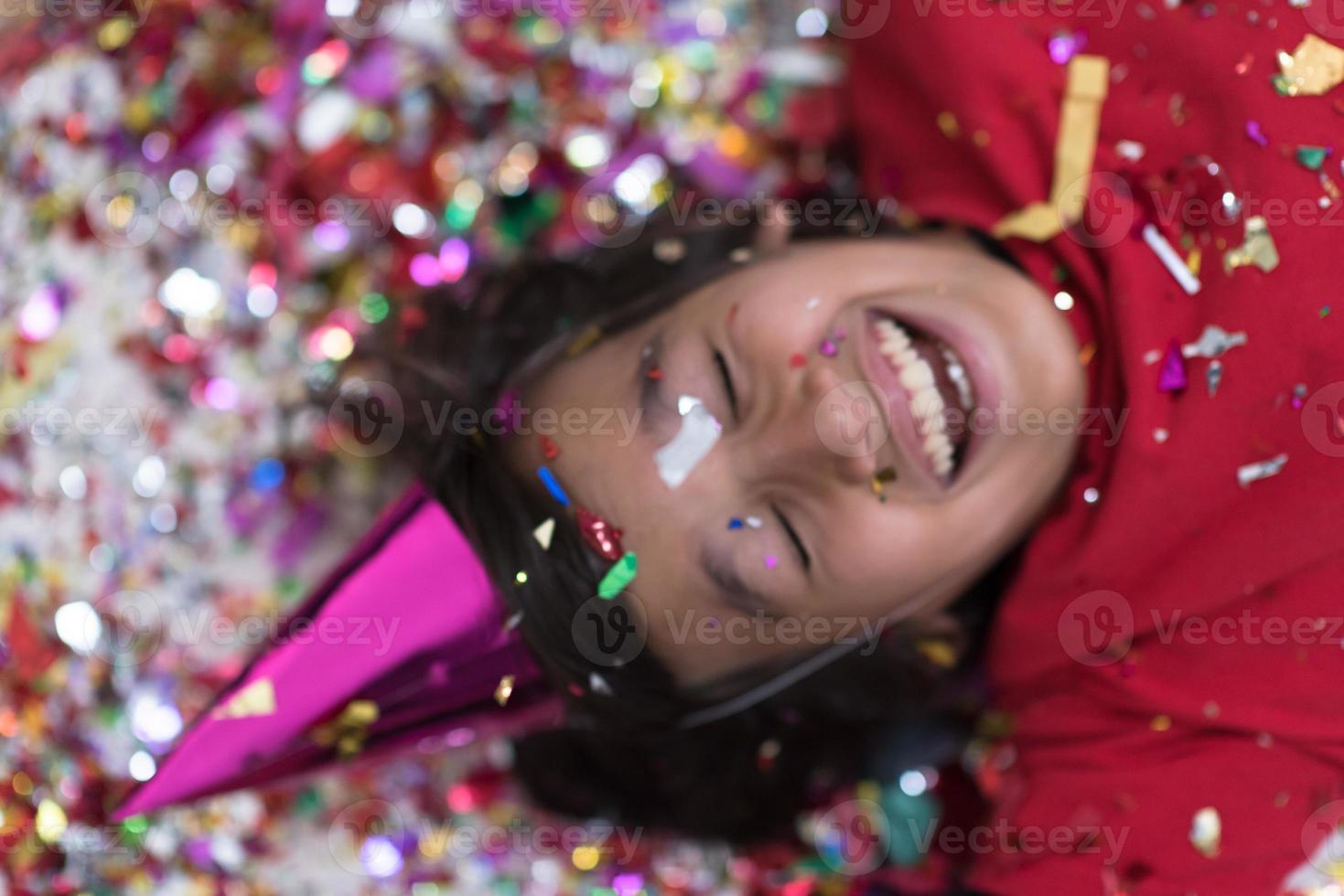 kid blowing confetti while lying on the floor photo