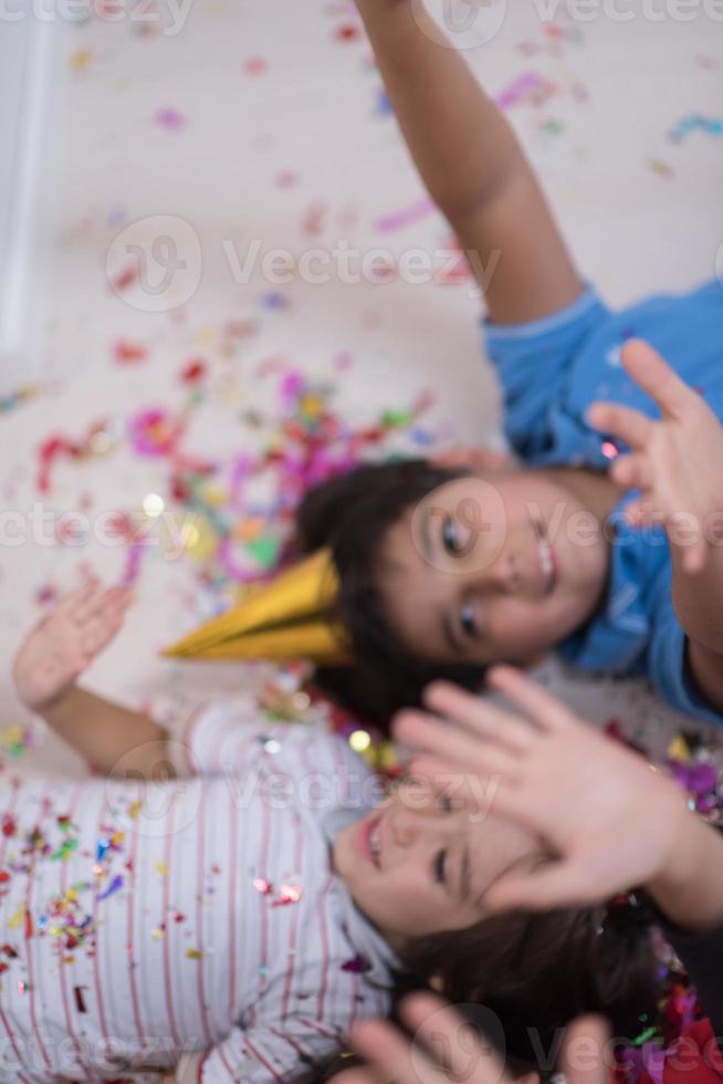 kids  blowing confetti while lying on the floor photo