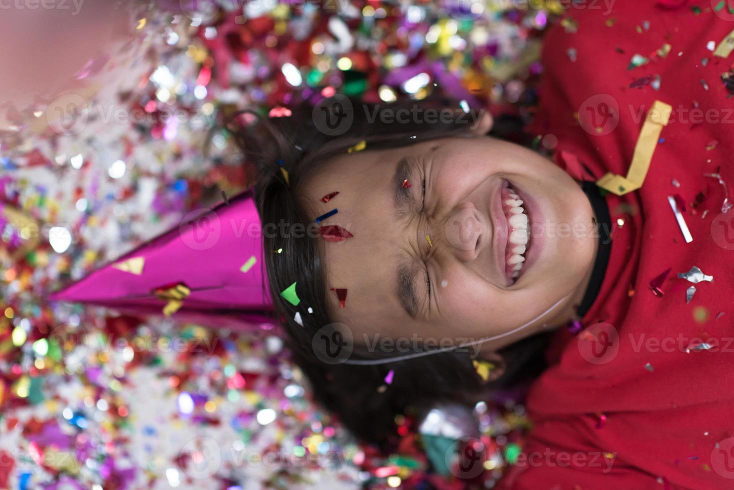 kid blowing confetti while lying on the floor photo