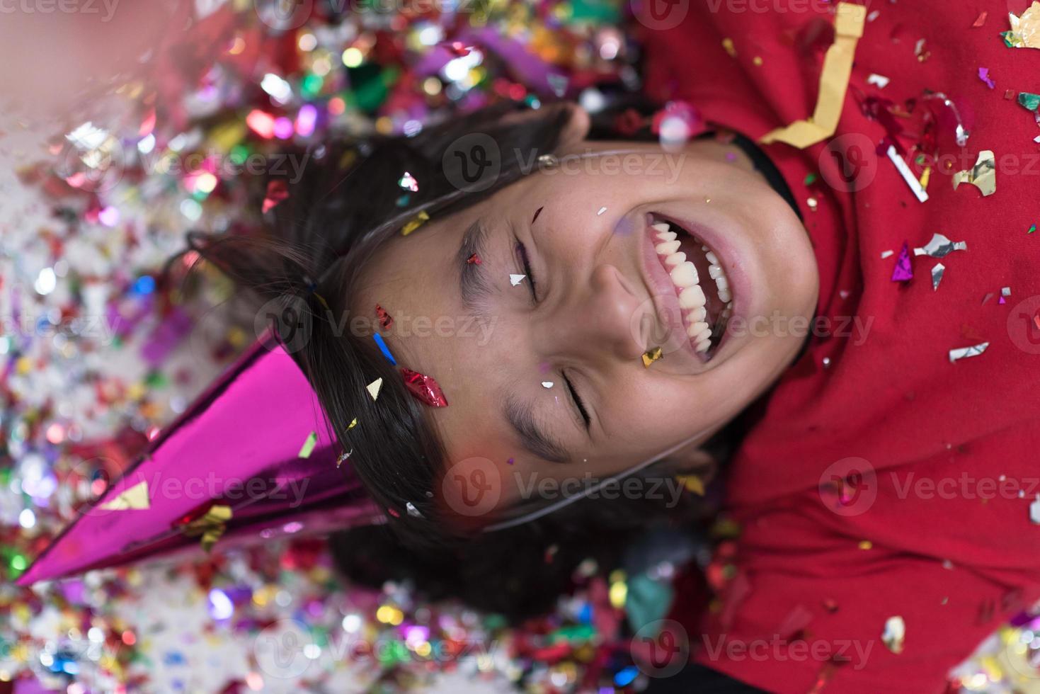 kid blowing confetti while lying on the floor photo