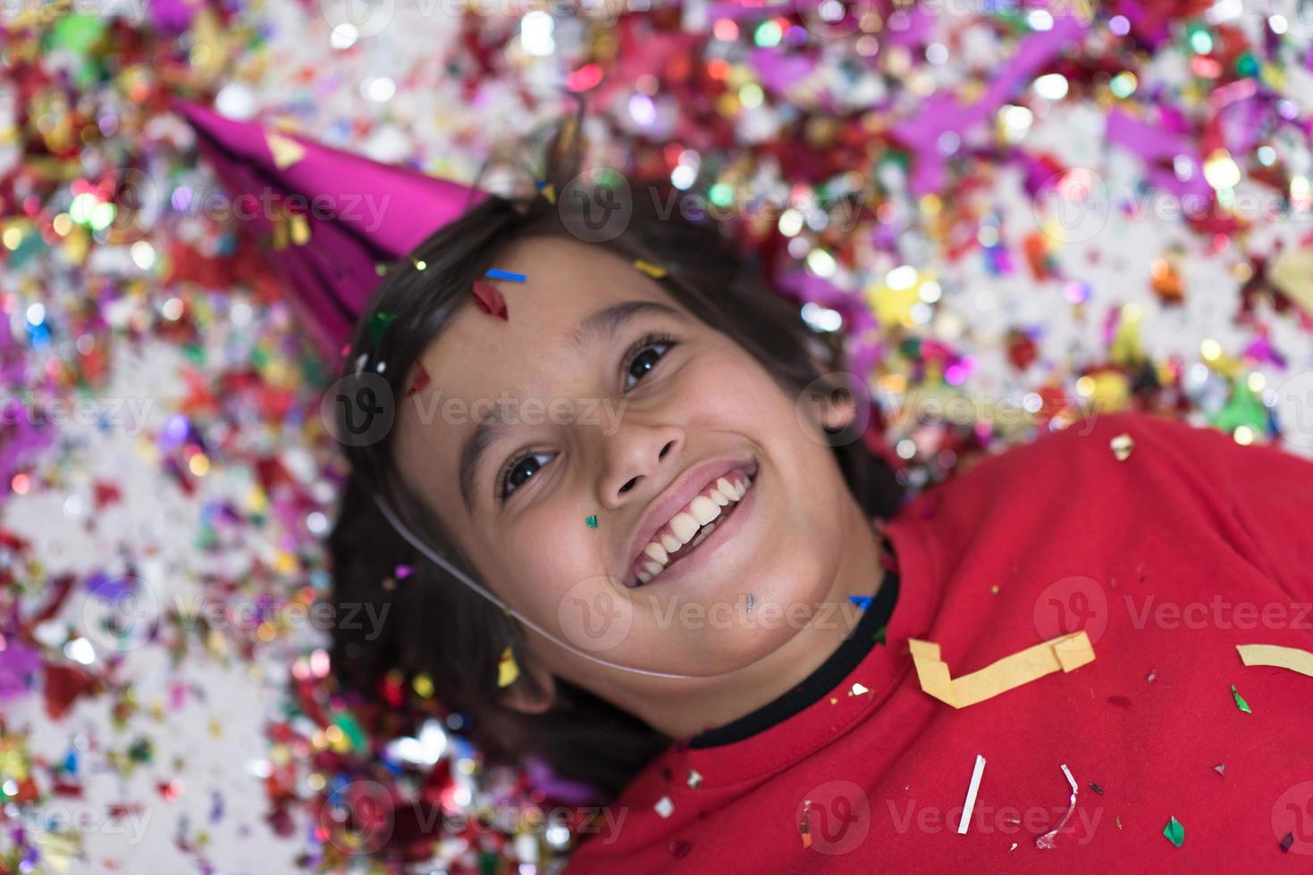 kid blowing confetti while lying on the floor photo