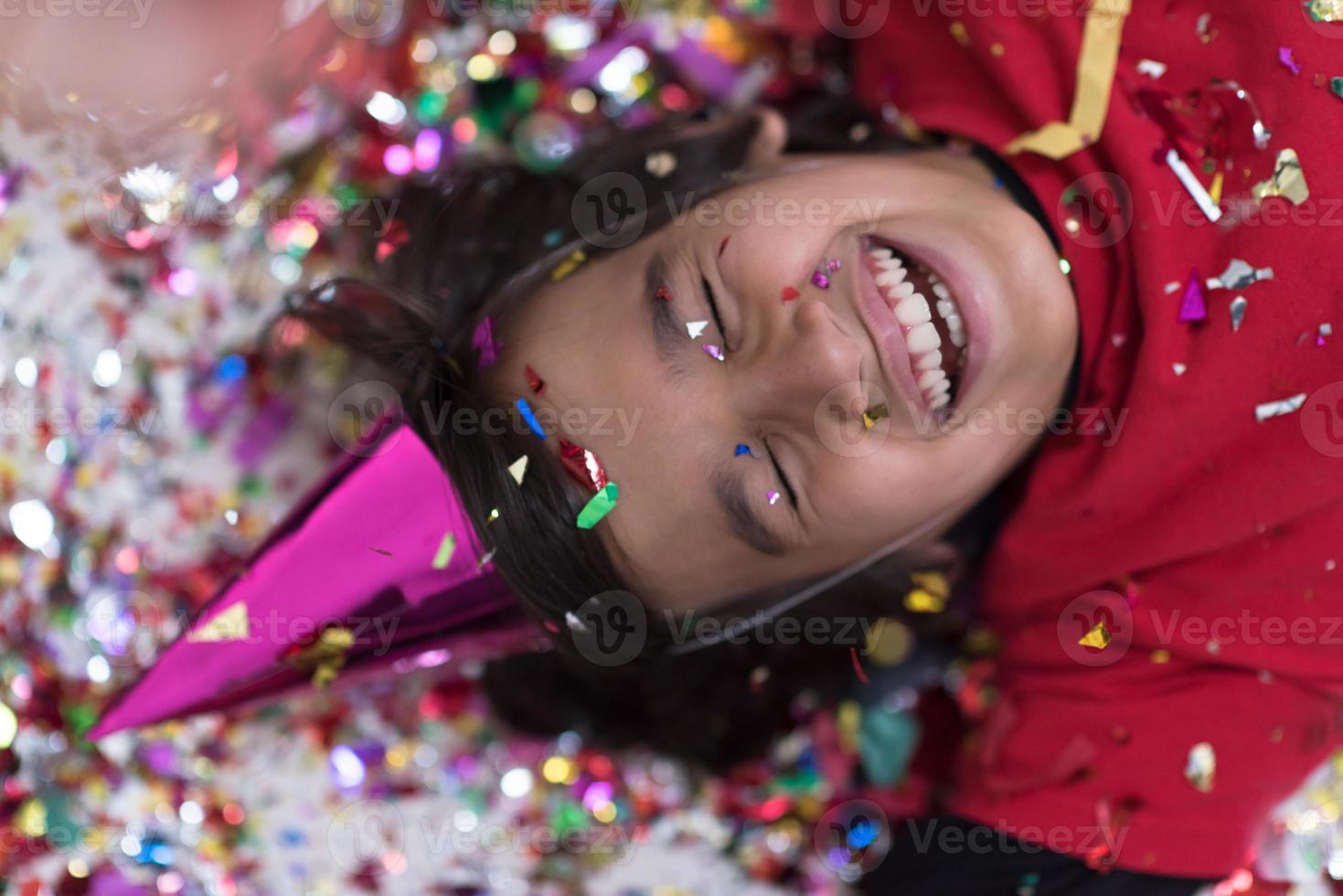 kid blowing confetti while lying on the floor photo