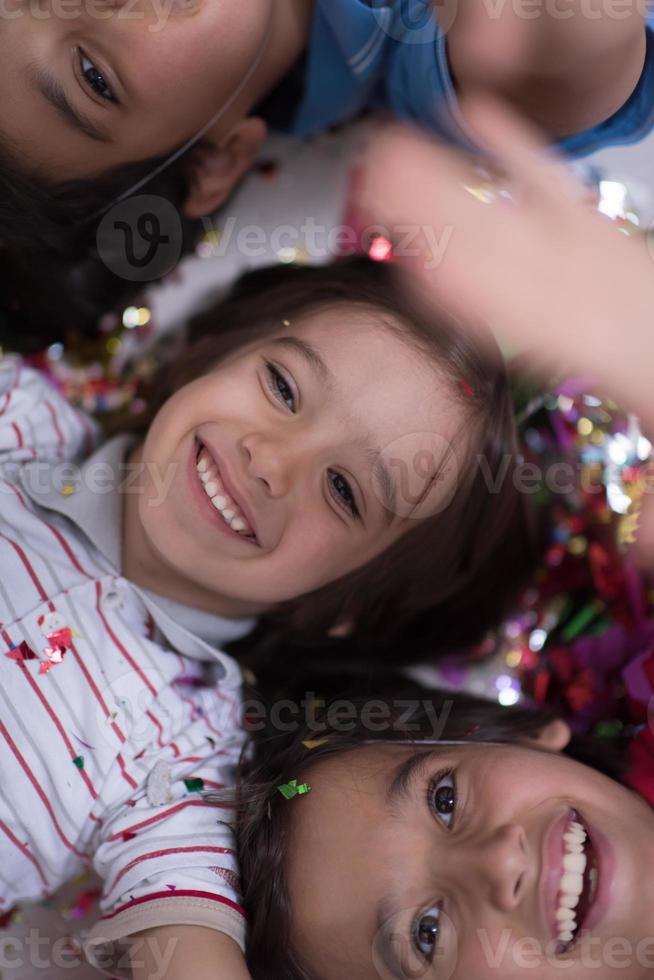 kids  blowing confetti while lying on the floor photo