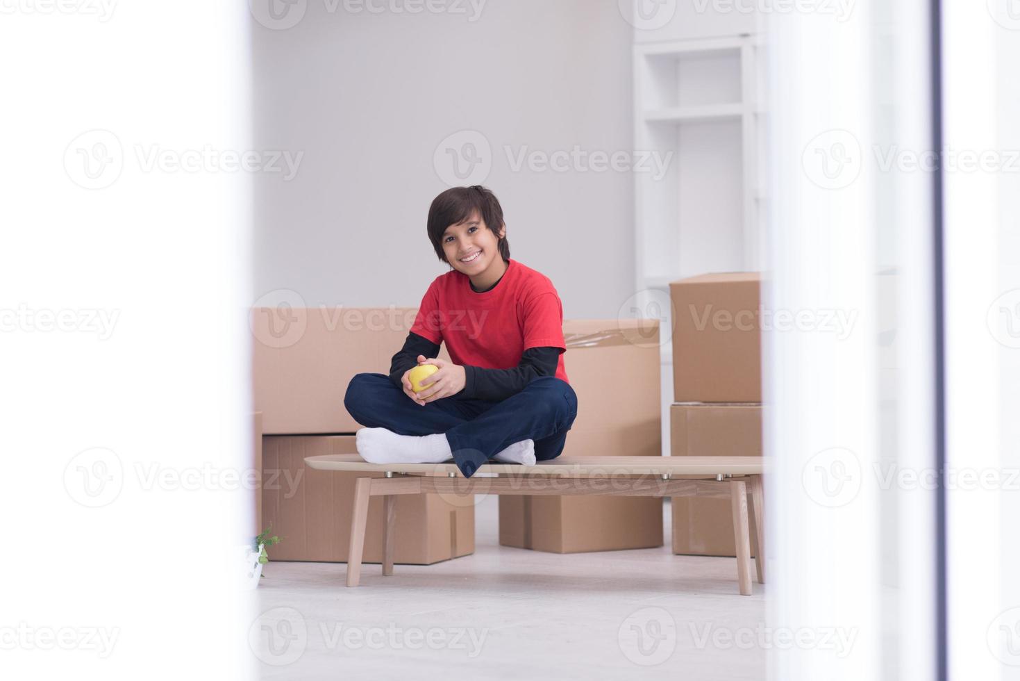 boy sitting on the table with cardboard boxes around him photo