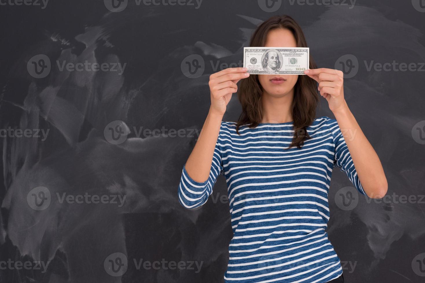 mujer sosteniendo un billete frente a un tablero de dibujo de tiza foto