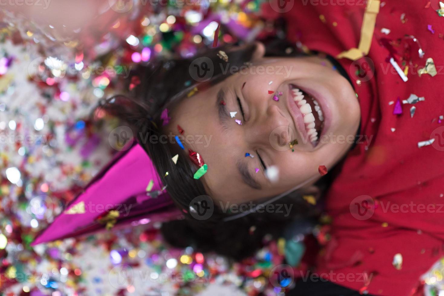 kid blowing confetti while lying on the floor photo