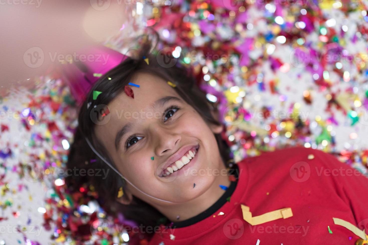 kid blowing confetti while lying on the floor photo