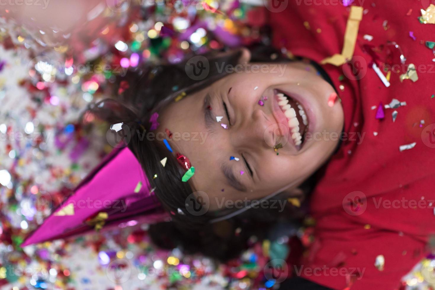 kid blowing confetti while lying on the floor photo