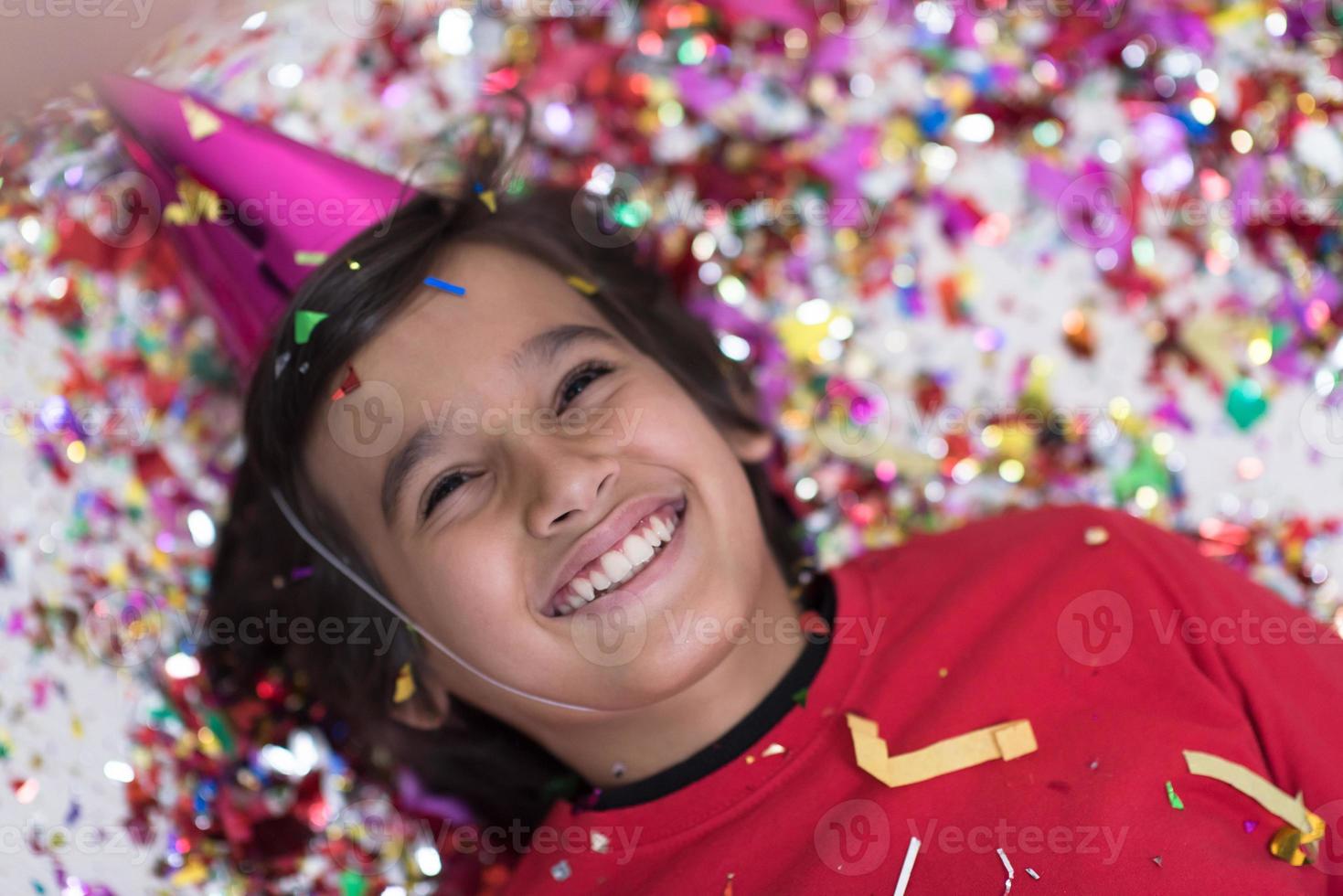 kid blowing confetti while lying on the floor photo