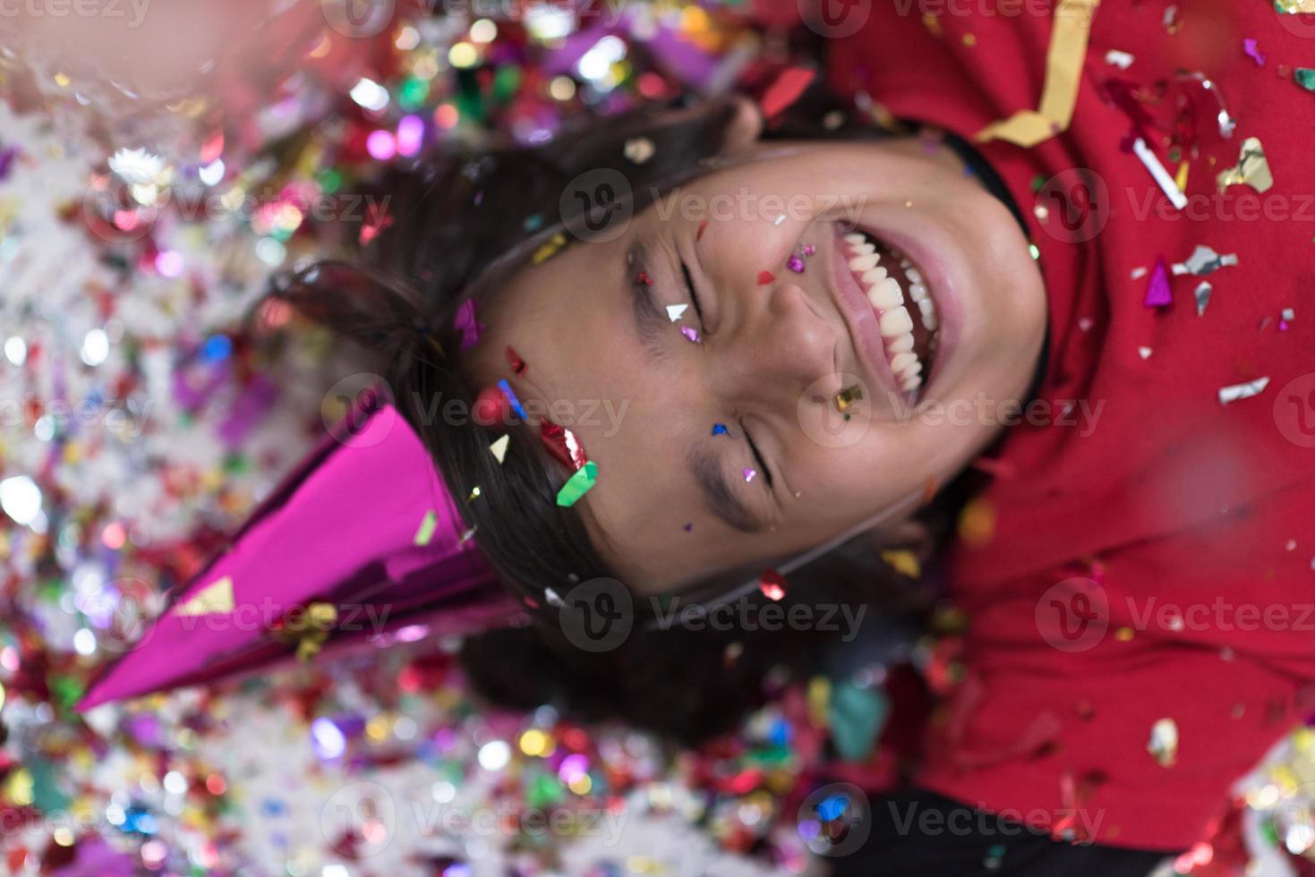 kid blowing confetti while lying on the floor photo