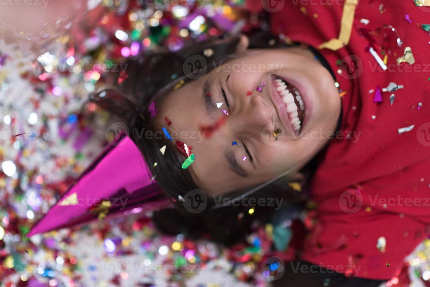 kid blowing confetti while lying on the floor photo
