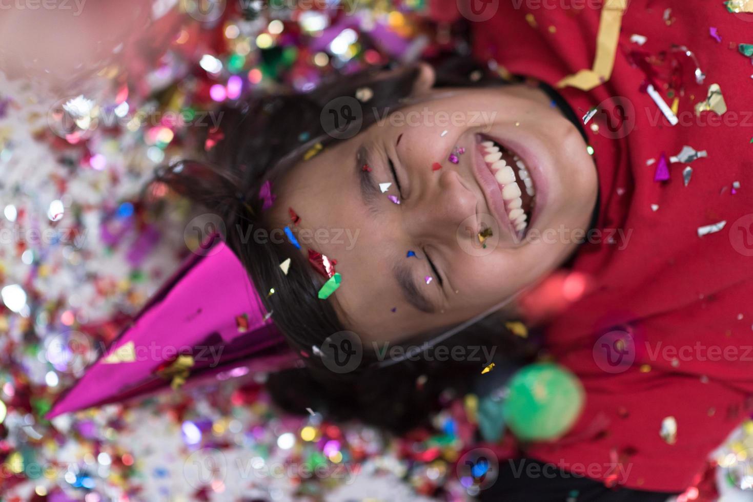 kid blowing confetti while lying on the floor photo
