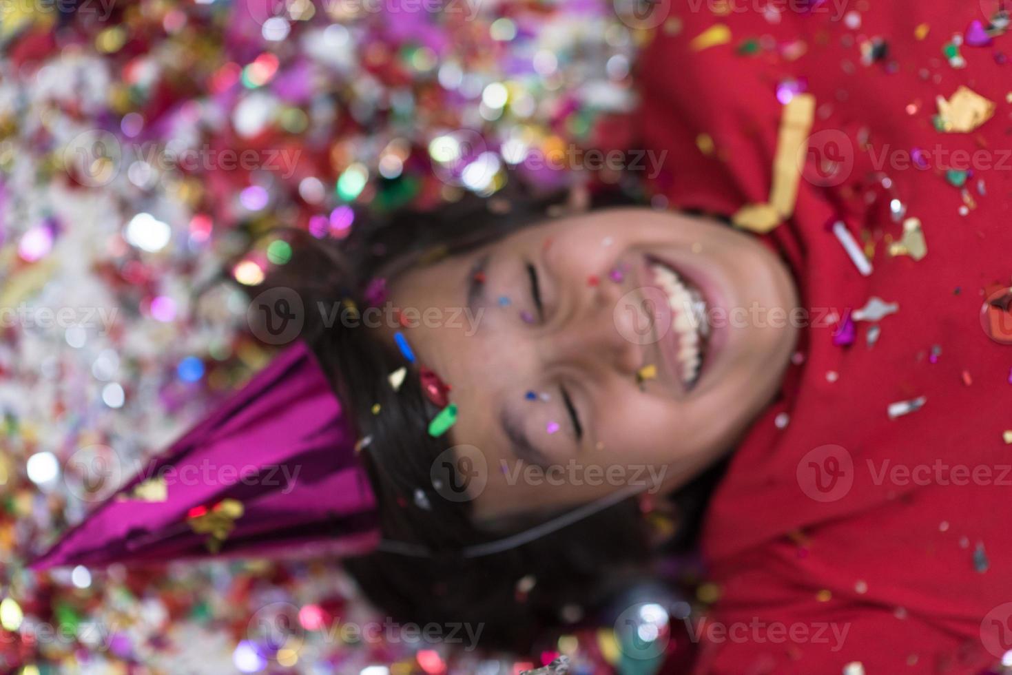 kid blowing confetti while lying on the floor photo
