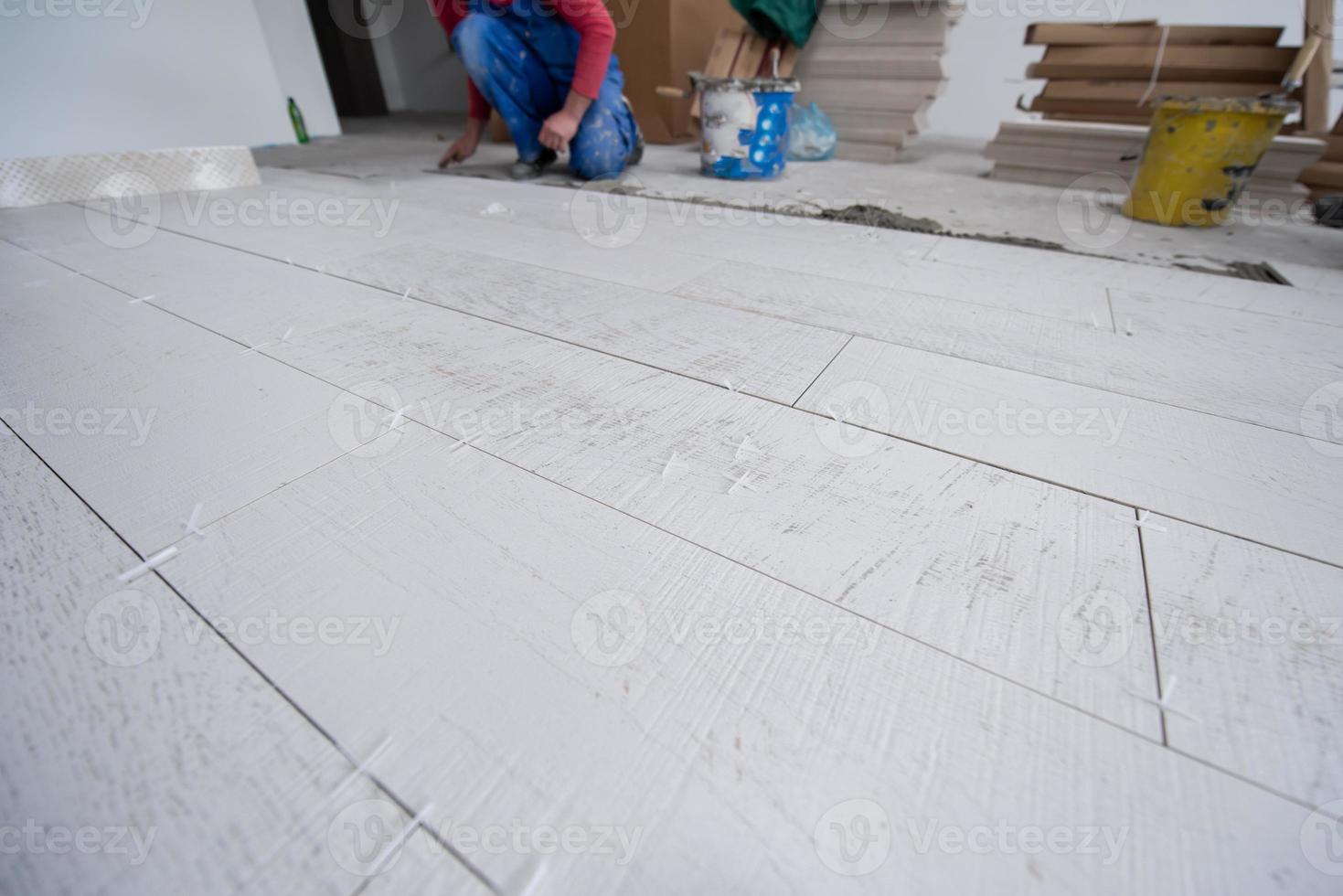 trabajador instalando las baldosas cerámicas con efecto madera en el suelo foto