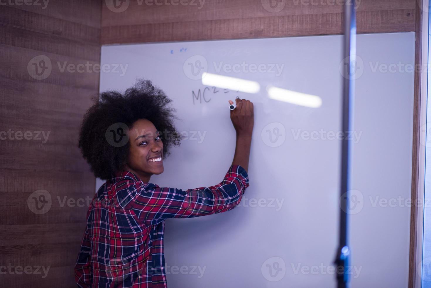 mujer afroamericana escribiendo en una pizarra en una oficina moderna foto