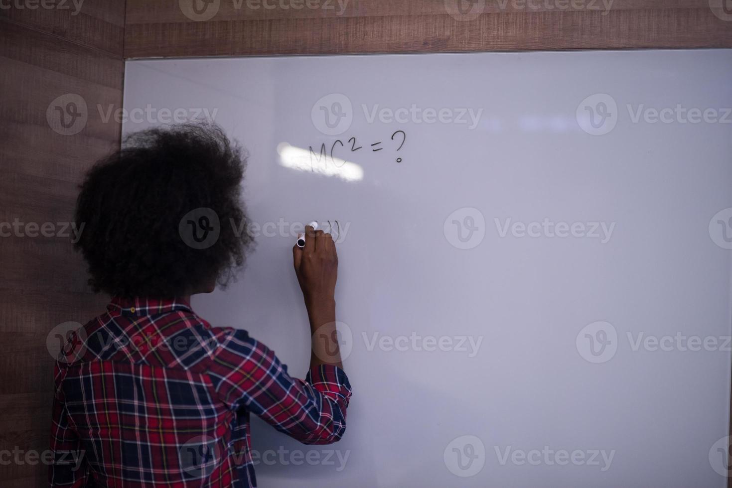 African American woman writing on a chalkboard in a modern office photo