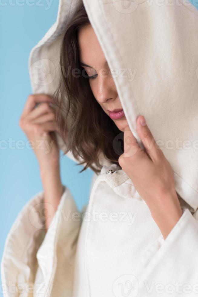 mujer en una bata blanca con capucha aislada sobre fondo azul foto