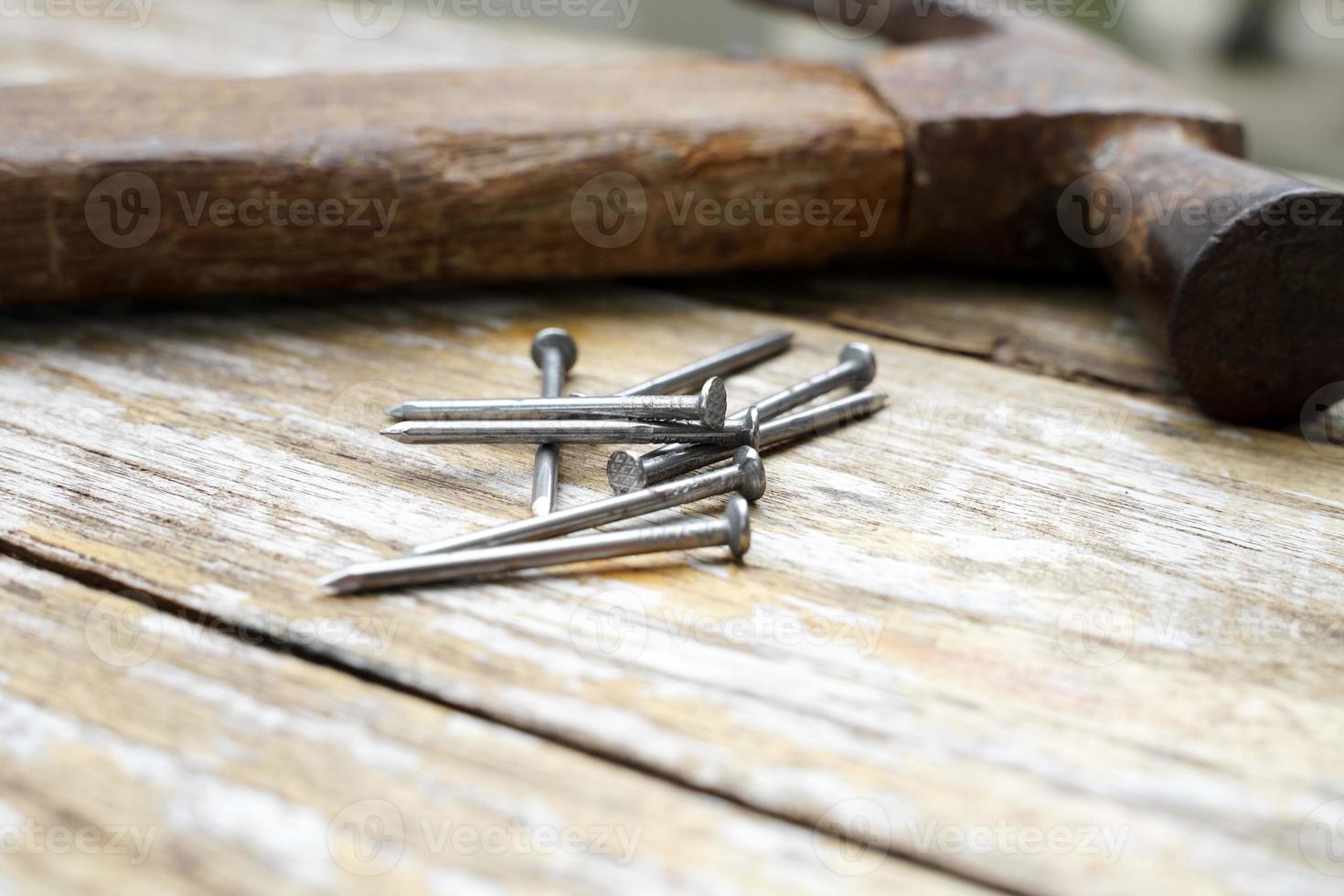 Hammer and nails on wooden background, wood and rust head iron hammer lying on wooden board with outdoor workshop. photo