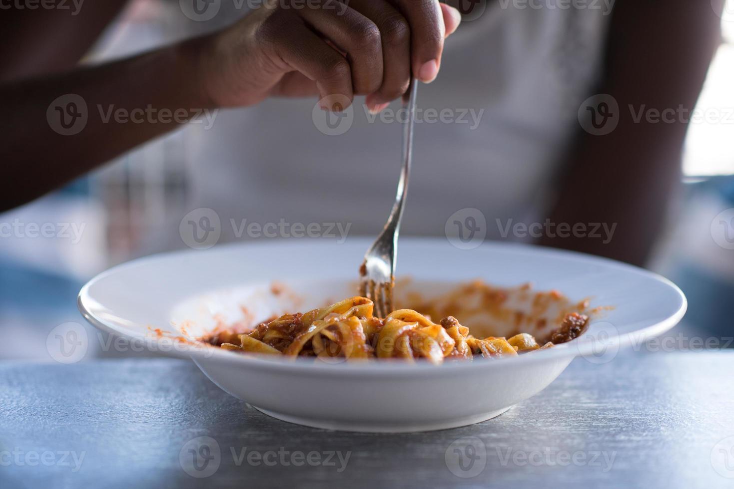 una joven afroamericana comiendo pasta foto