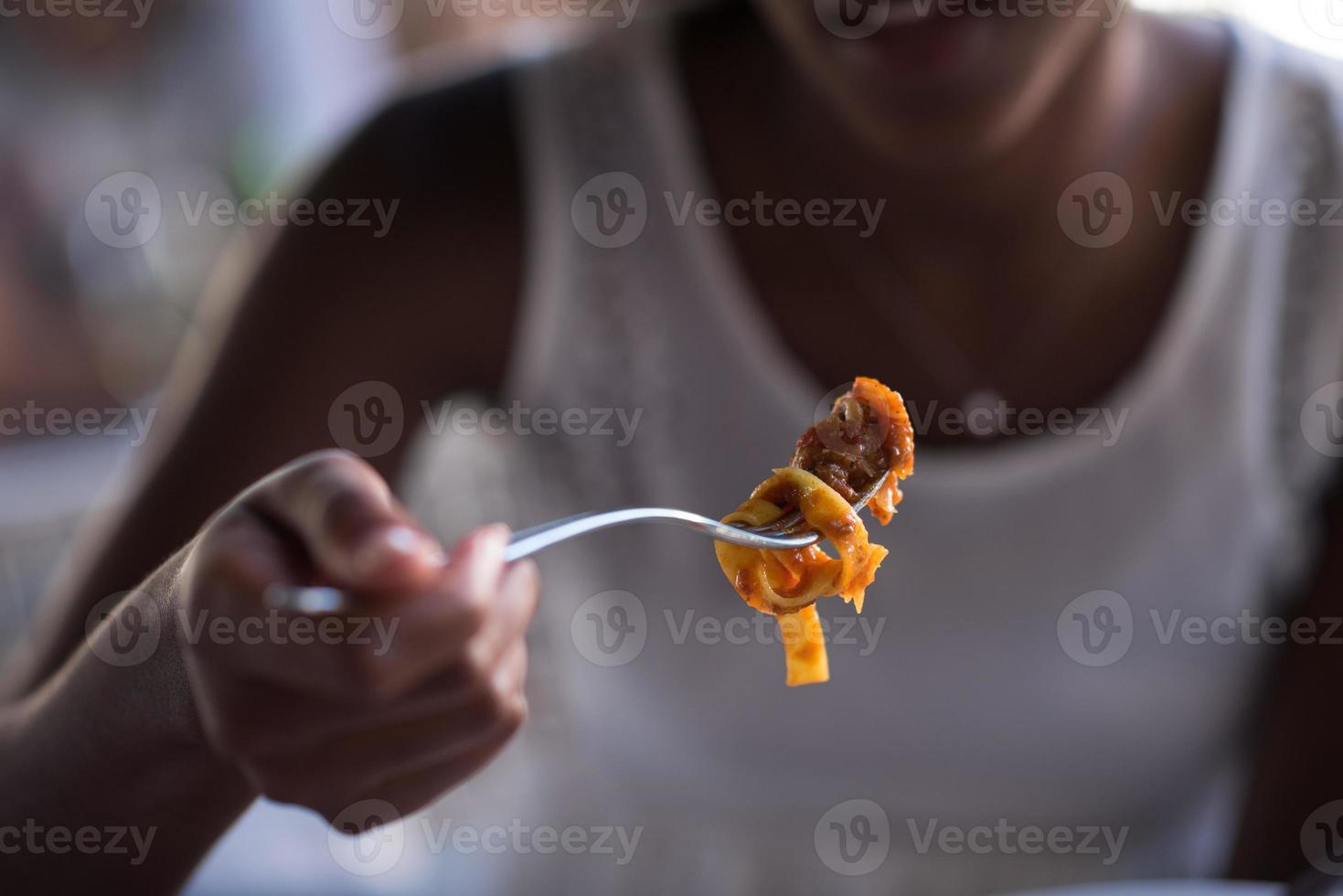 a young African American woman eating pasta photo