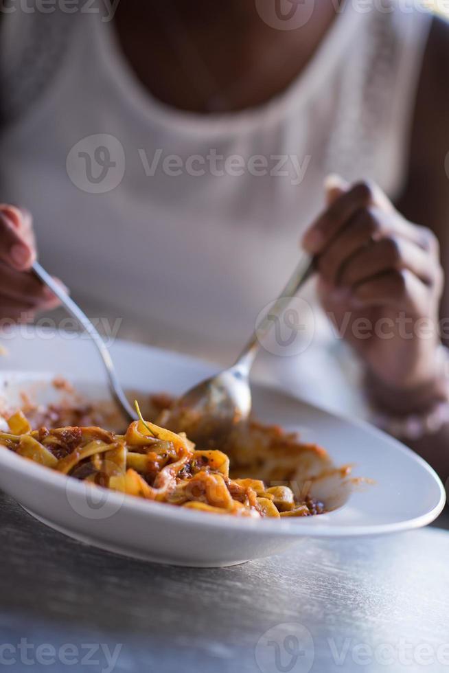 a young African American woman eating pasta photo