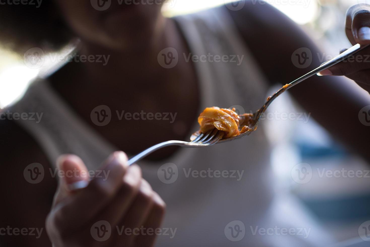 a young African American woman eating pasta photo