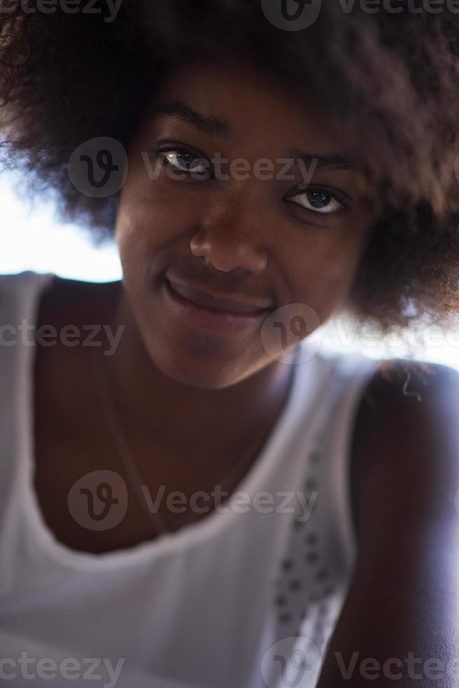 primer plano retrato de una hermosa joven afroamericana sonriendo y mirando hacia arriba foto