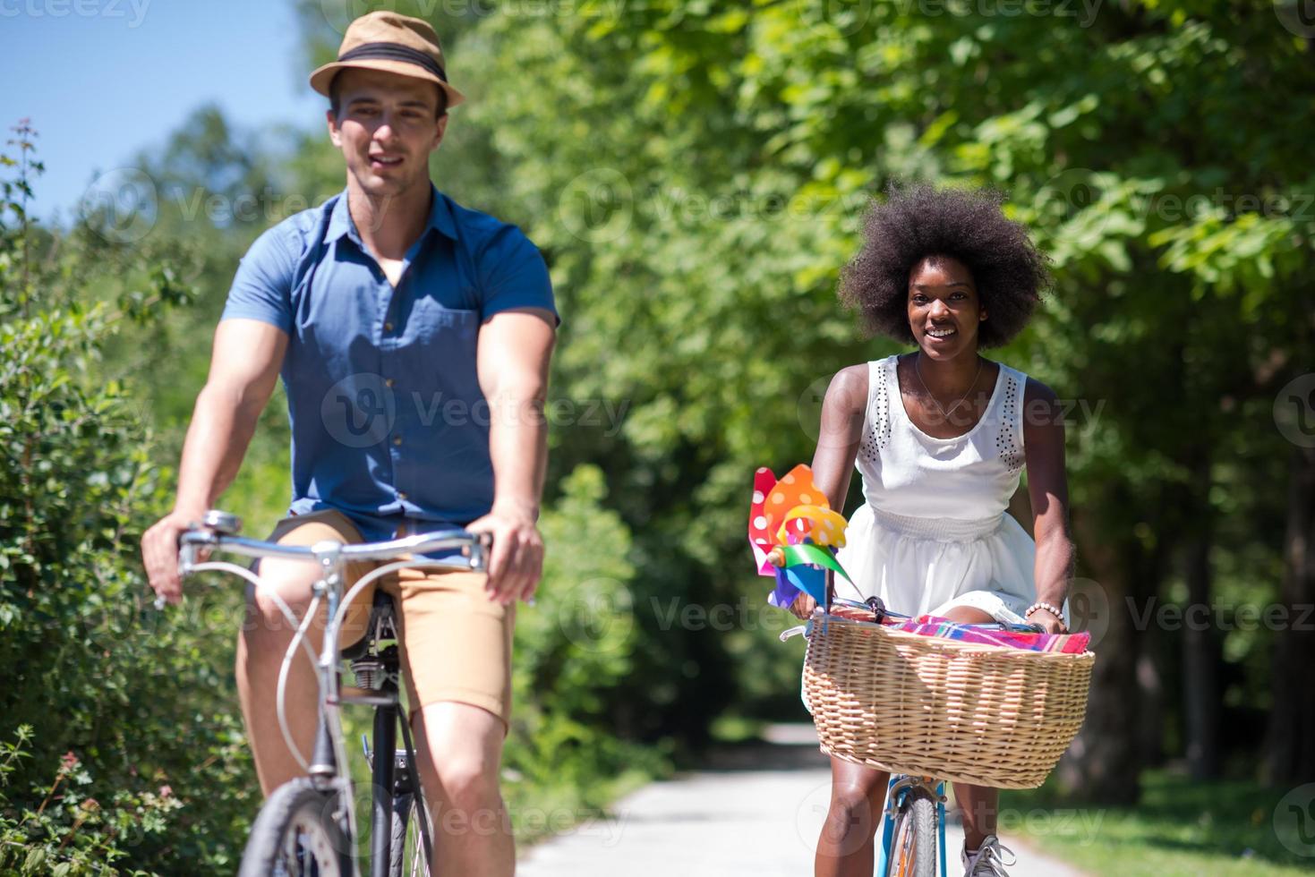 joven pareja multiétnica dando un paseo en bicicleta en la naturaleza foto