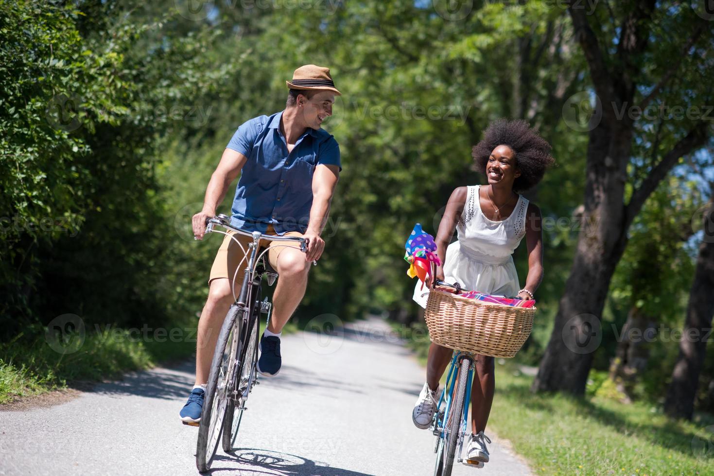 joven pareja multiétnica dando un paseo en bicicleta en la naturaleza foto