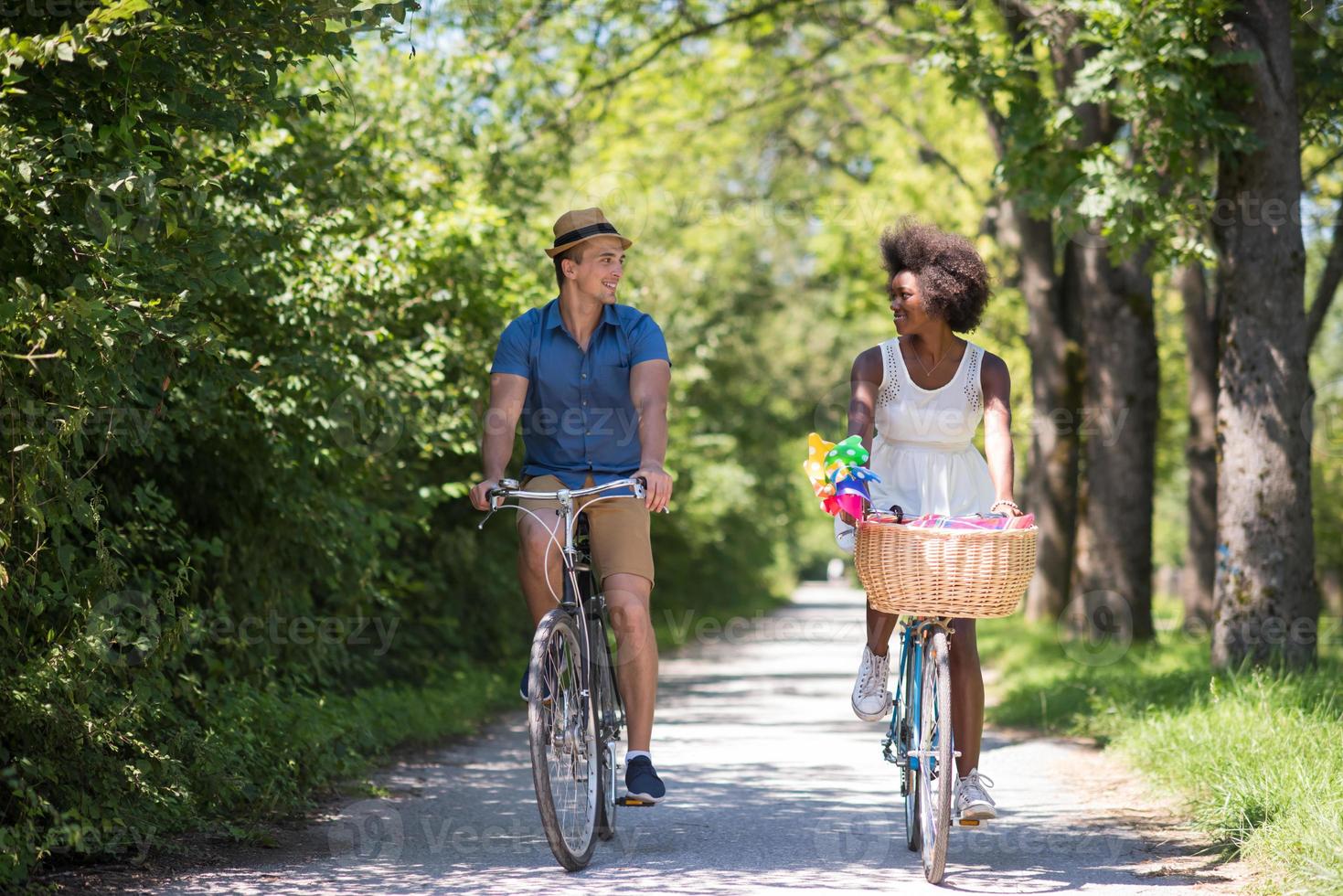 joven pareja multiétnica dando un paseo en bicicleta en la naturaleza foto