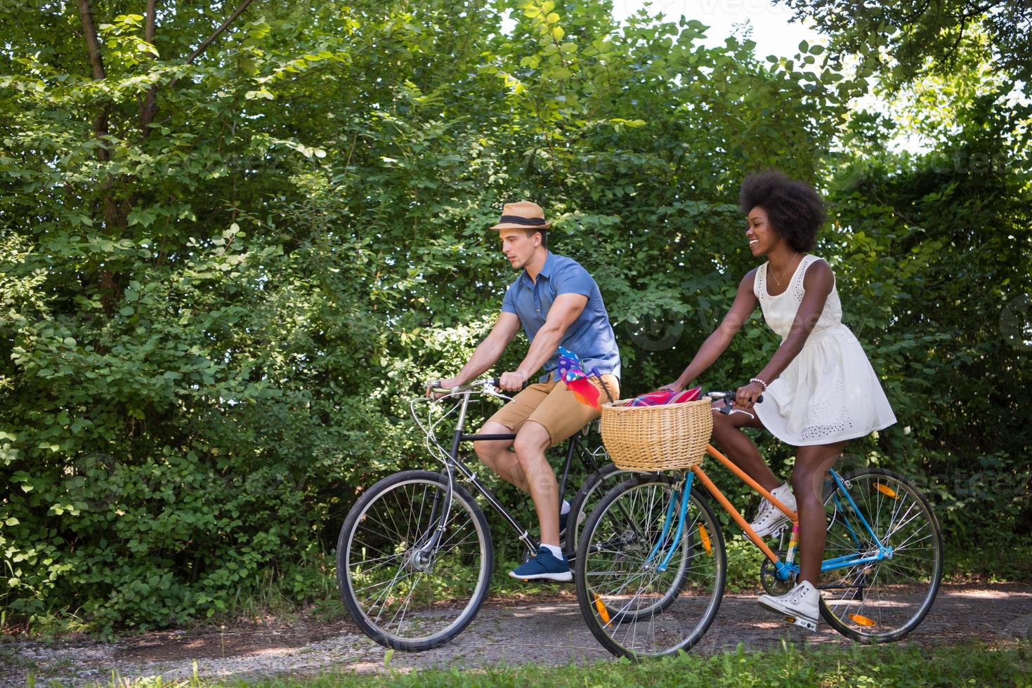 joven pareja multiétnica dando un paseo en bicicleta en la naturaleza foto