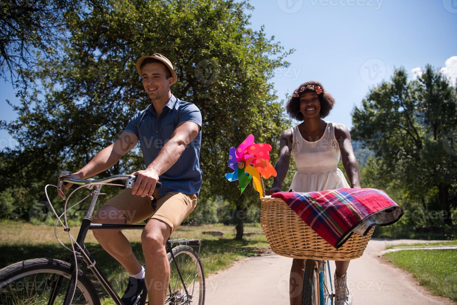 joven pareja multiétnica dando un paseo en bicicleta en la naturaleza foto